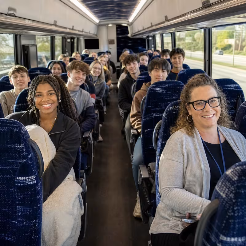 Group boarding a white charter bus for School Transportation transportation in Fontana